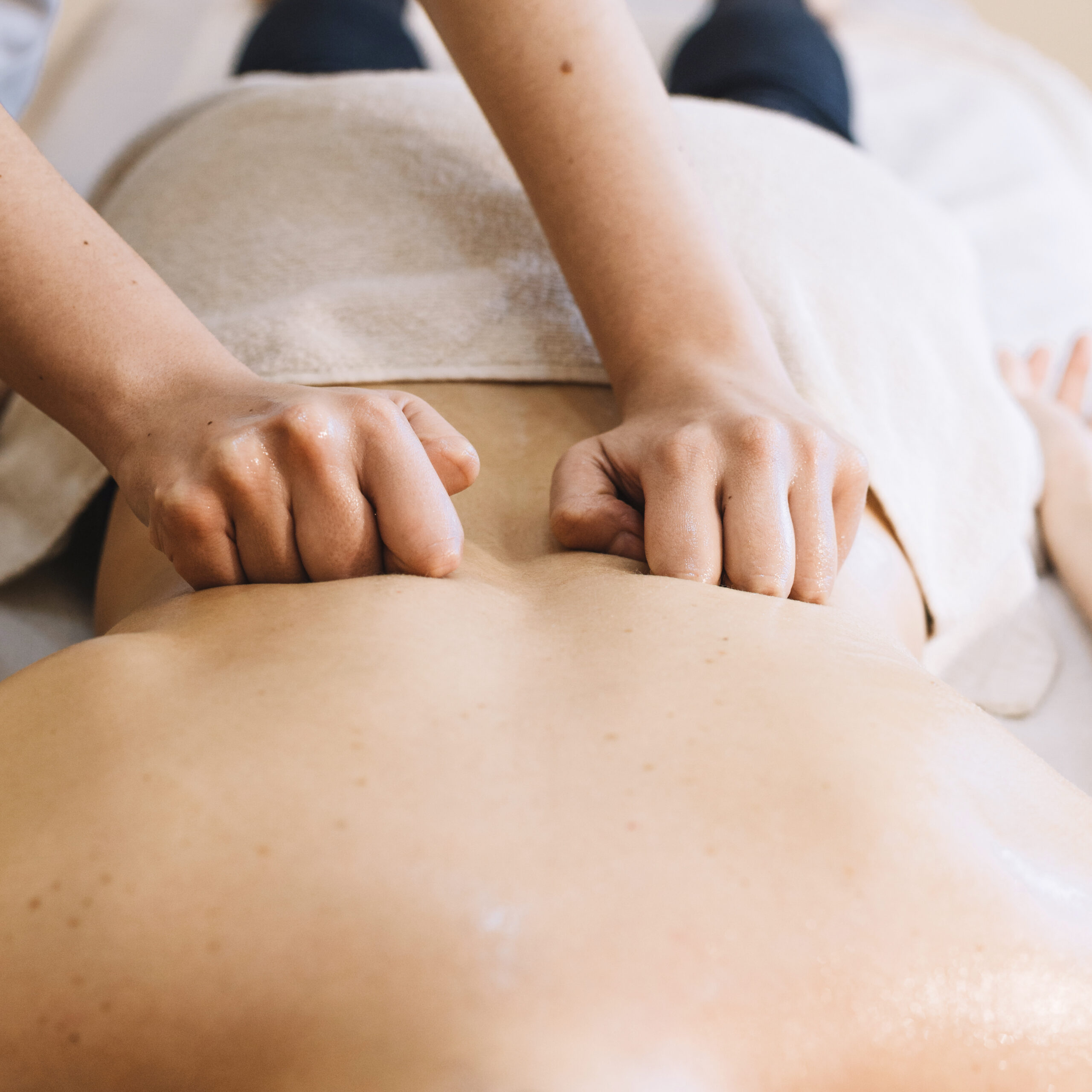 Ruhige Massagesituation mit Handtüchern, Öl und warmer Atmosphäre.