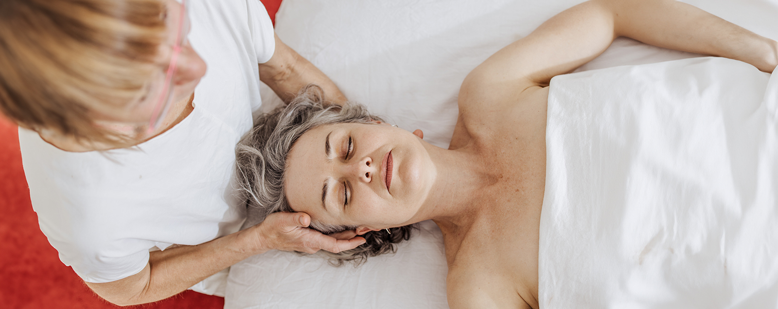 Intuitive Massage: Doris Sattelberger begleitet eine Klientin mit achtsamer Berührung im Schulter- und Nackenbereich.