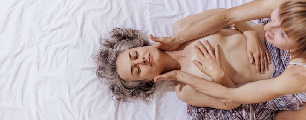 Sinnliche Massage und achtsame Körperarbeit: Eine Klientin liegt entspannt, während Doris Sattelberger sanft den Schulter- und Nackenbereich berührt.